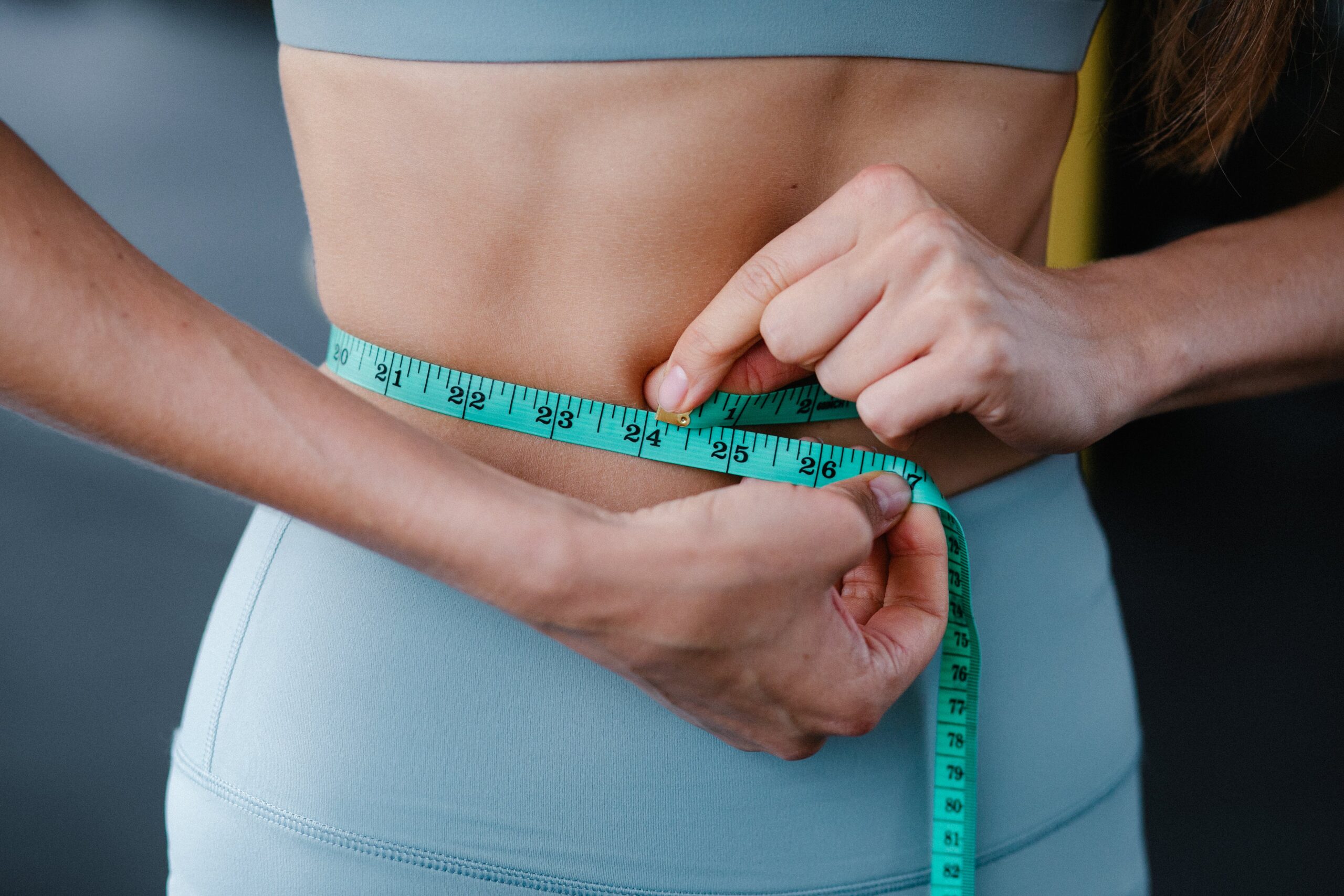 Weight Loss solutions- woman measuring herself.